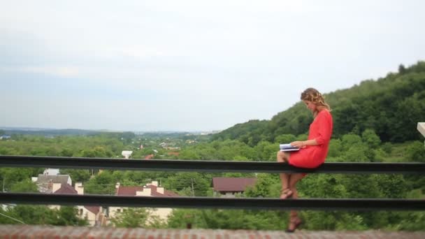 Vacker kvinna sitter på en bänk i parken och läsa en bok, Student som förbereder för examen i trädgården, ung kvinna avkopplande på en parkbänk — Stockvideo