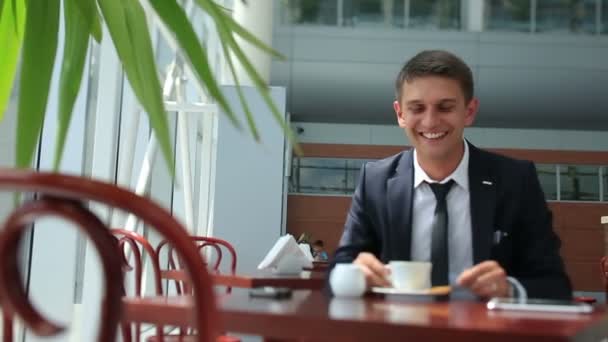 Счастливый бизнесмен пьет черный кофе, сидит в ярком кафе — стоковое видео