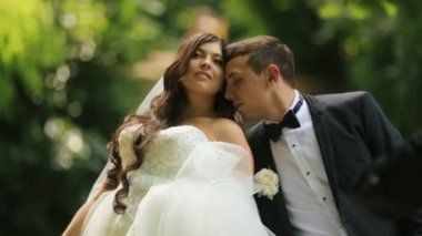 Sevgi dolu damat güneşli yaz park onun büyüleyici gelin omuz öper. Açık hava düğün yavaş hareket ile vurdu