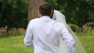 Yeni evliler eğleniyor. Damat oynak gelin ve onlar için her iki gülüyor çalışır. Açık yaz park ile arka plan olarak vurdu.