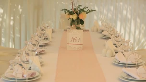 Table de mariage luxueuse avec bouquet floral, numéro de réception sur carte mignonne, verres et assiettes — Video