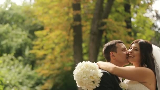 Felice sposa appena sposata e sposo baciare, rendendosi conto che sono sposati ora. Colpo all'aperto con parco estivo come sfondo — Video Stock