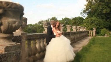 Sevgi dolu damat güzel gelini boynundan, eski taş korkuluk Park yakınındaki kucaklayan kisses