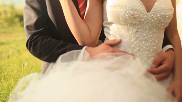 Любящий жених в черном костюме нежно обнимает свою красивую белую невесту на улице. Камера медленно поднимает от талии до лица молодоженов — стоковое видео