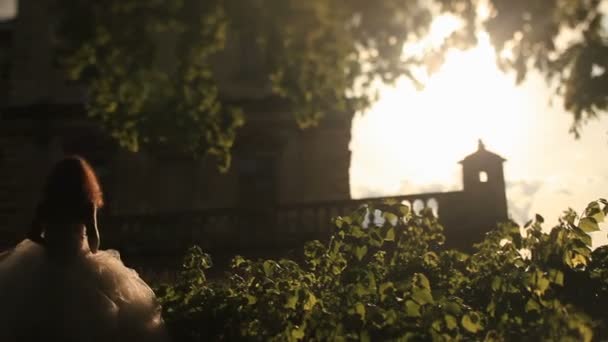 Beyaz elbise güzel gelin sıcak gün batımı ışınları'romantik vintage Palace'e onun yakışıklı damat ile yürüyor — Stok video
