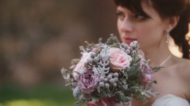 Pembe gül buketi açık havada tutarak ve kamera dışında seyir düşünceli gelin