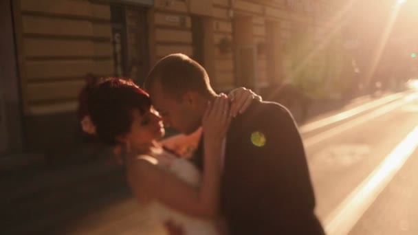 Νεόνυμφο ζευγάρι αγκαλιάζει στοργικά στο ηλιοβασίλεμα στο δρόμο στην παλιά ευρωπαϊκή πόλη — Αρχείο Βίντεο