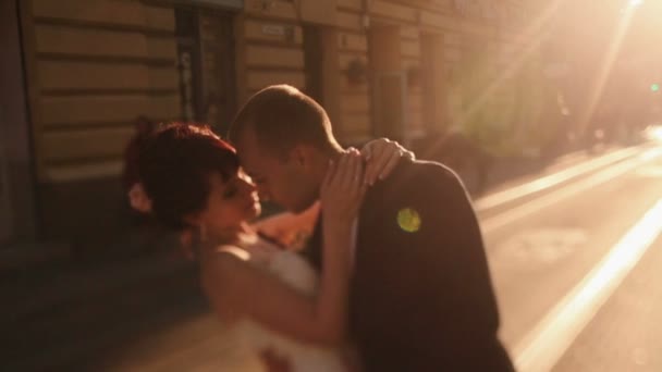 Jonggehuwde paar omarmt liefdevol bij zonsondergang straat in de oude Europese stad — Stockvideo