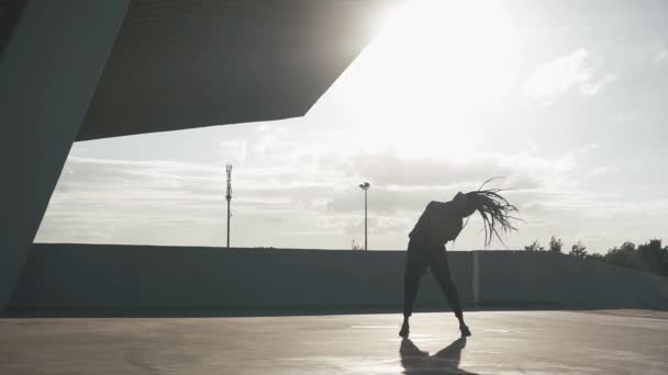 Утренняя тренировка. Здоровая молодая женщина смешанной расы с дредами, растягивающимися на открытом воздухе в замедленной съемке — стоковое видео