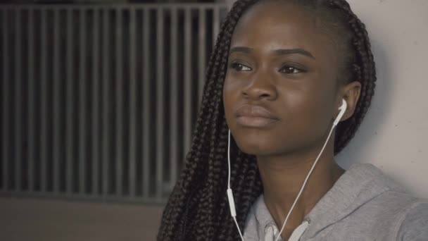 이어폰에서 음악을 듣고 웃 고 험 상을 매력적인 아프리카계 미국인 여자의 얼굴을 클로즈업 — 비디오