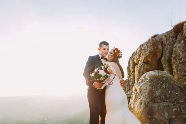 Romántica pareja recién casada en las luces del atardecer de otoño en majestuoso acantilado rocoso de montaña —  Fotos de Stock