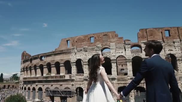 Emocionada pareja de boda en Roma por el Coliseo sosteniendo sus manos. Luna de miel en Italia, Europa — Vídeo de stock