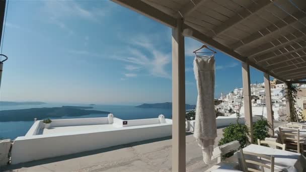 Gros plan robe de mariée de fête soufflant dans le vent sur la terrasse avec la mer bleue sur le fond — Video