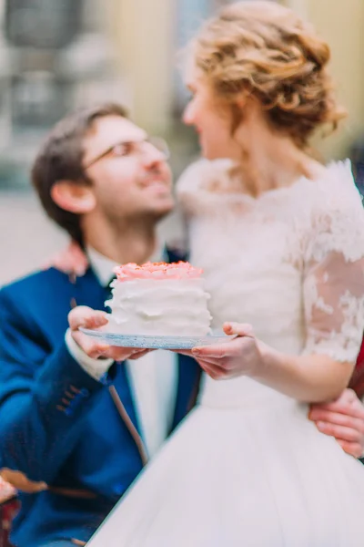Casal de casamento encantador segurando seu bolo de casamento de perto — Fotografia de Stock