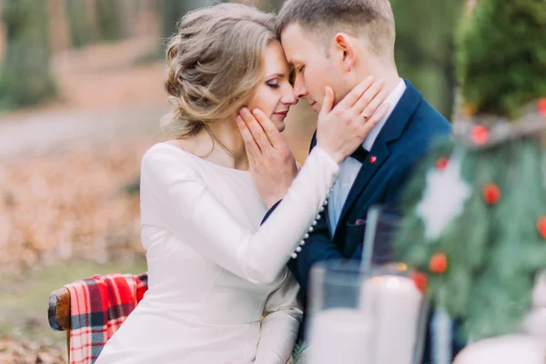 Charming wedding couple softly stroking face of each other at the holiday table in autumn forest — Stock Photo, Image