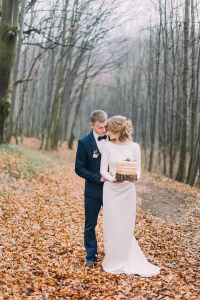 Feliz casal jovem casamento andando e abraçando perto da mesa decorada para férias de Natal na floresta de outono . — Fotografia de Stock