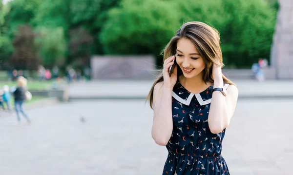 Mladými, krásnými dlouhými vlasy brutette žena mluvila telefonicky v městském parku — Stock fotografie