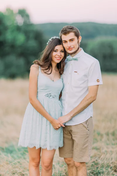 Porträt eines jungen glücklichen stilvollen Paares, das auf dem Sommerfeld posiert. Grüner Wald im Hintergrund — Stockfoto