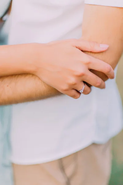 Cerca de las manos de la atractiva pareja joven en una cita caminando juntos en el parque y abrazándose unos a otros alrededor de la cintura — Foto de Stock