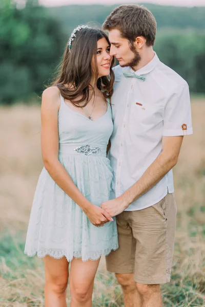 Porträt eines jungen glücklichen stilvollen Paares, das am Sommerfeld steht. Grüner Wald im Hintergrund — Stockfoto