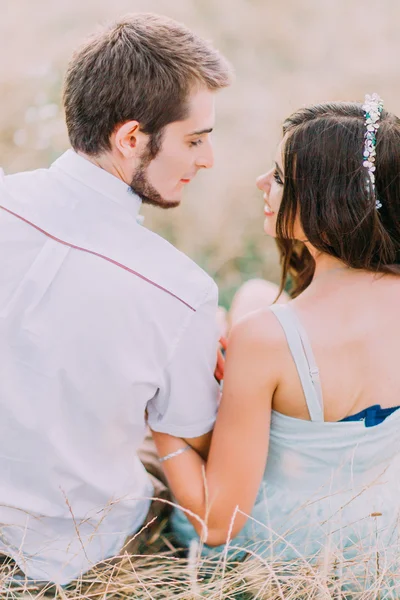 Retrato al aire libre de una hermosa pareja sentada en el campo de trigo. Vista trasera —  Fotos de Stock