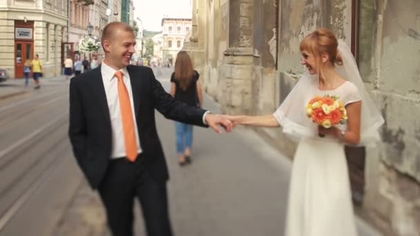 Casal de casamento alegre andando nas ruas da cidade antiga com bela arquitetura — Vídeo de Stock