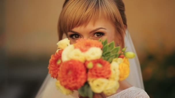 Чарівна блондинка наречена з весільним букетом уважно дивиться в камеру — стокове відео