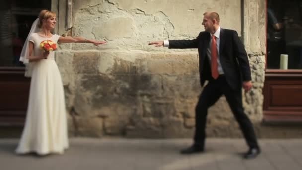 Vidám esküvő házaspár szórakozás a régi Lviv város utcáin — Stock videók