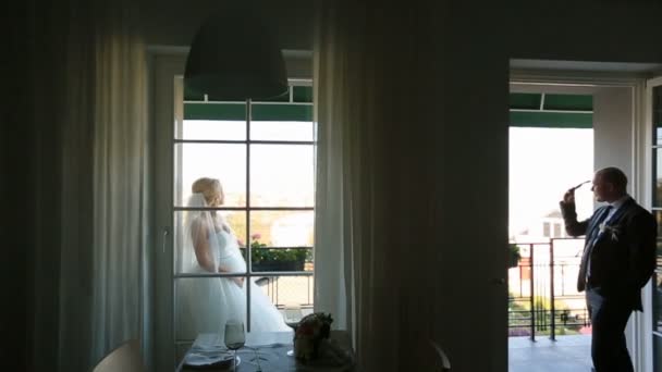 Mooie sexy bruid en knappe bruidegom scheiden op balkon in het resort. Huwelijksreis concept — Stockvideo
