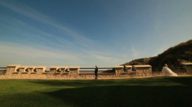 Beyaz elbiseli mutlu genç sarışın gelin damada eski ortaçağ kalesi arka planda çalışır.