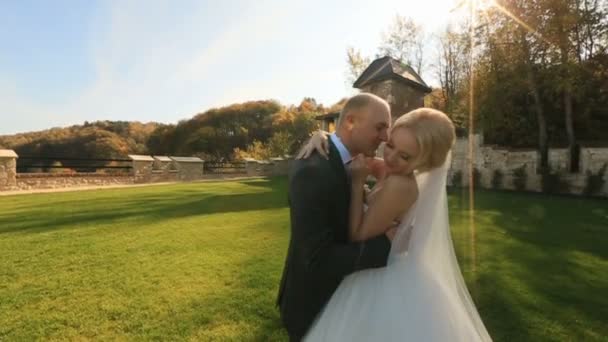 Feliz recém-casados amorosamente beijando suavemente em seu dia do casamento no pátio do castelo medieval — Vídeo de Stock