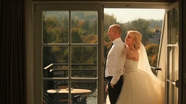 美丽性感的新娘与英俊的新郎拥抱在阳台上。蜜月概念 — 图库视频影像
