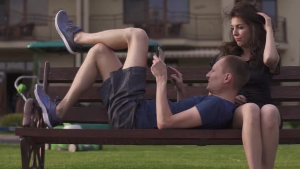 Квартал між двома молодими людьми в парку через гаджети — стокове відео