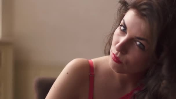 Крупный план красивой сексуальной брюнетки с красными губами, соблазнительно смотрящей в камеру — стоковое видео