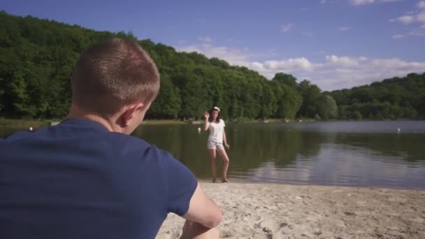 Брюнетка дівчина кидає у воді її boyfriends смартфон і сміятися. — стокове відео