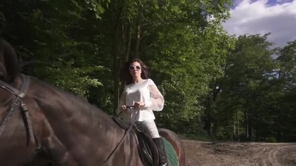 Brunette dans les promenades blanches cheval dans le parc au jour du printemps — Video