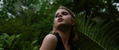 Yeşil ferns tarafından çevrili ormandaki şehvetli genç kadının aşağıdan görüntülemek