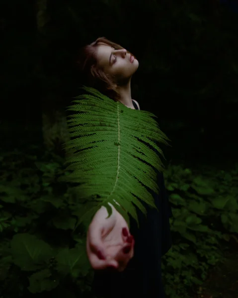 Sígueme en el bosque. Retrato surrealista de chica encantadora con los ojos cerrados tirando de la mano y sosteniendo la hoja de helecho — Foto de Stock