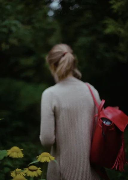 Menina loira com a mochila vermelha andando no parque verde — Fotografia de Stock