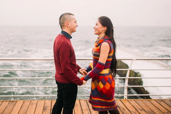 Pareja brillante y elegante tomados de la mano y con amor se miran el uno al otro en la litera. Fondo marino. Una maravillosa luna de miel. — Foto de Stock