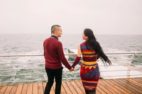 Bright stylish couple having fun and holding hands on the berth. Sea background. Wonderful honeymoon — Stock Photo, Image