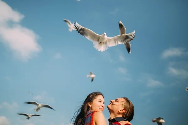 Portrait of romantic bright couple happily embracing and cheerfully smile. Indah tenang langit biru dengan burung camar terbang di latar belakang — Stok Foto