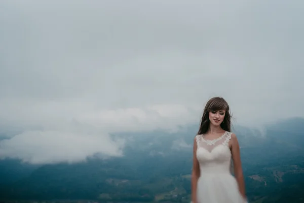 Piękna panna młoda w białej sukni pozowanie na górze — Zdjęcie stockowe