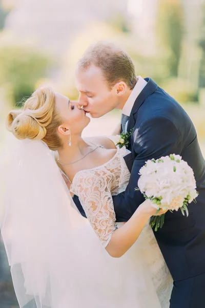 Beautiful kissing wedding couple in spring nature close-up portrait — Stock Photo, Image