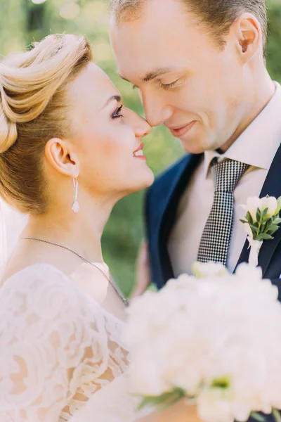 Vackra bruden och brudgummen embracing på deras bröllopsdag utomhus. Soliga våren park bakgrund — Stockfoto