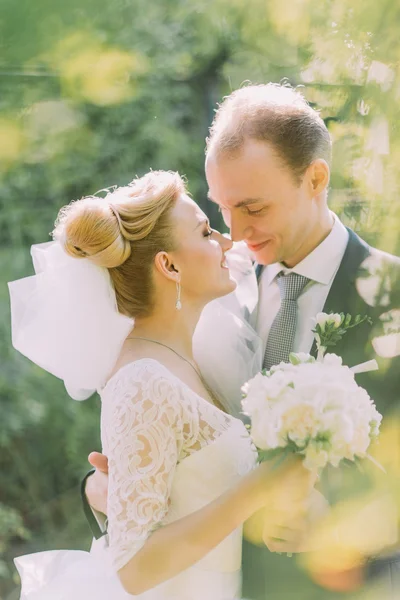 Porträtt av bruden och brudgummen omfamna på sin bröllopsdag utomhus. Sunny Spring Park bakgrund — Stockfoto