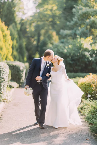 幸せな若い結婚式カップル春公園で一緒に歩くとグリーン レーンにキス. — ストック写真