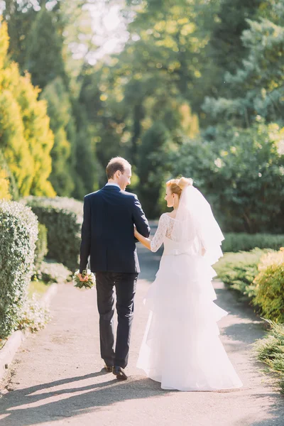 Glückliches junges Hochzeitspaar beim gemeinsamen Spaziergang im Frühlingspark. zurück — Stockfoto
