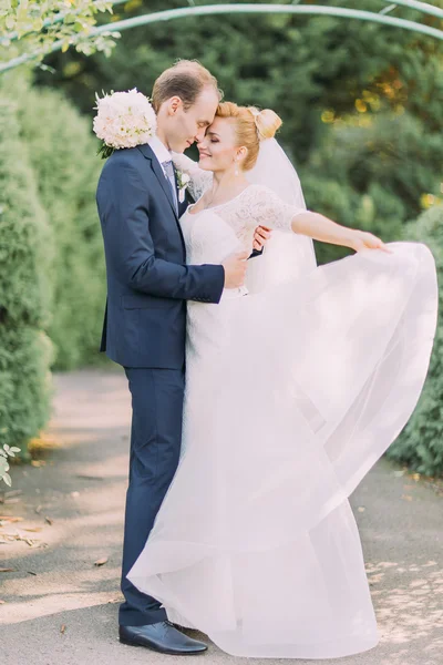 新郎と花嫁は公園で静かに抱き合う。手に花のブライダル結婚式の花束 — ストック写真
