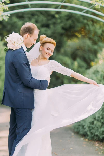 公園でポーズをとる若い優しい新郎と花嫁を幸せに。手に花のブライダル結婚式の花束 — ストック写真